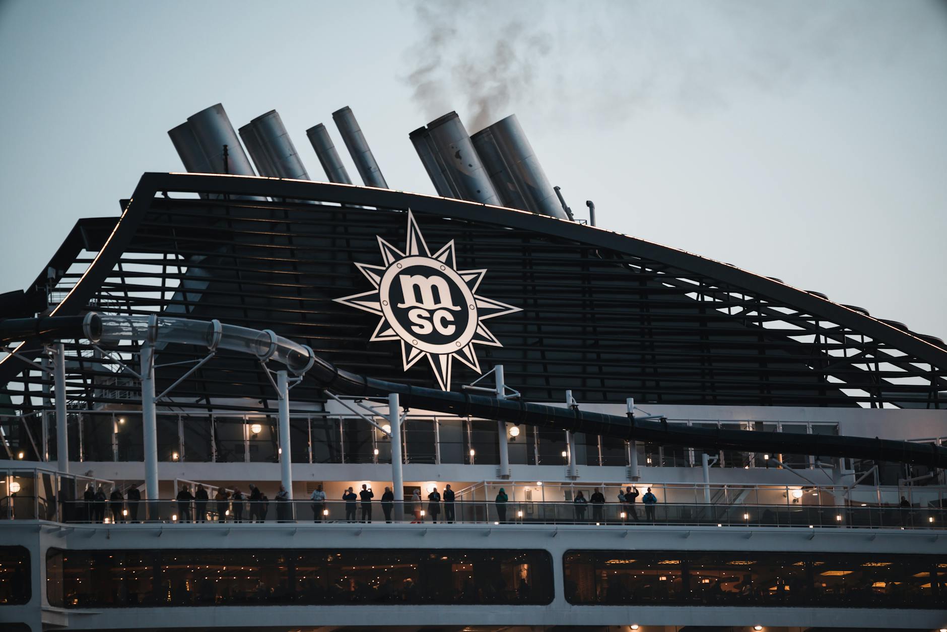 Passengers on MSC cruise ship deck enjoying an evening view of the smokestacks and sea
