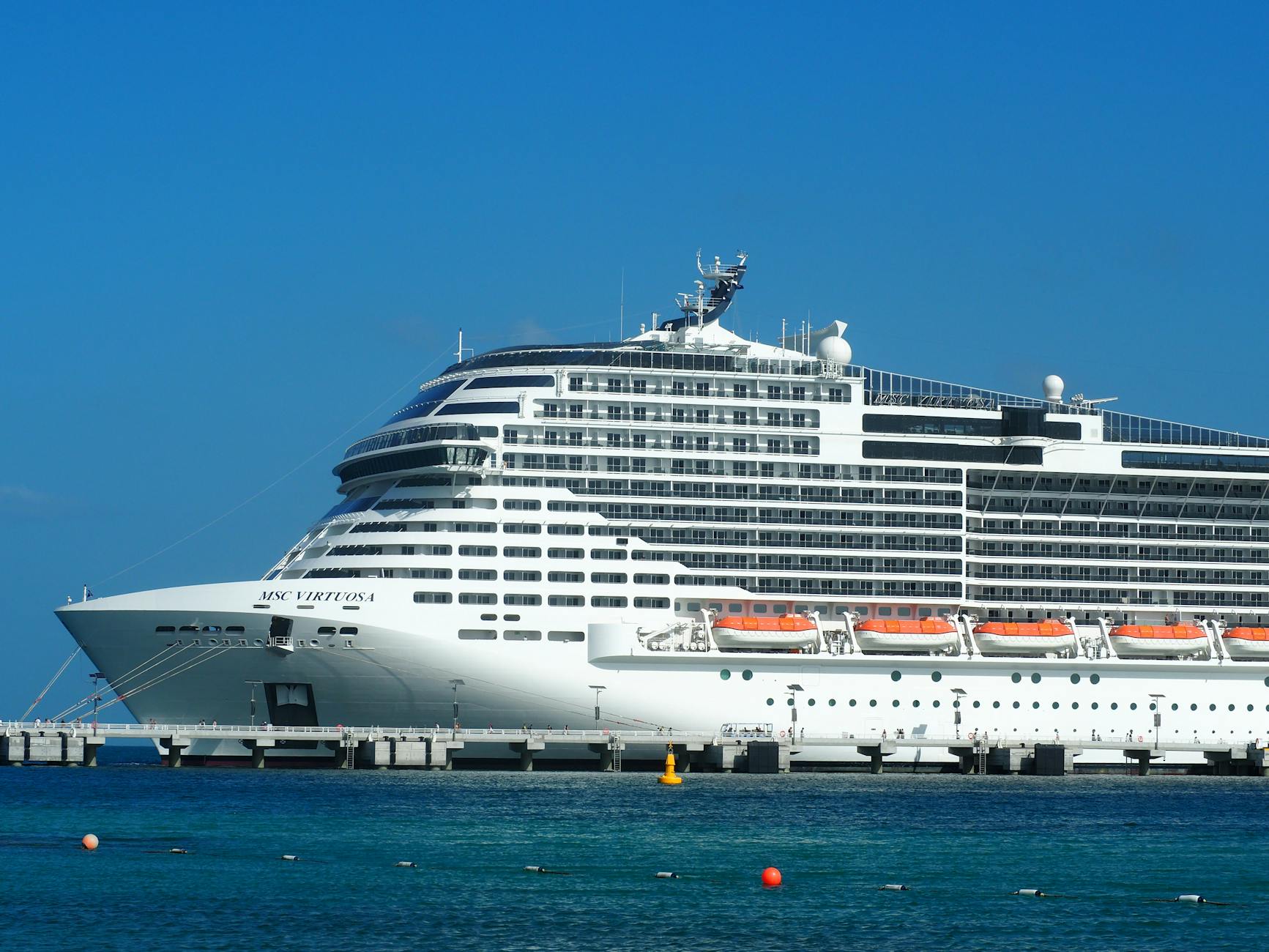 MSC Virtuosa cruise ship docked at a sunny harbor with blue water and sky