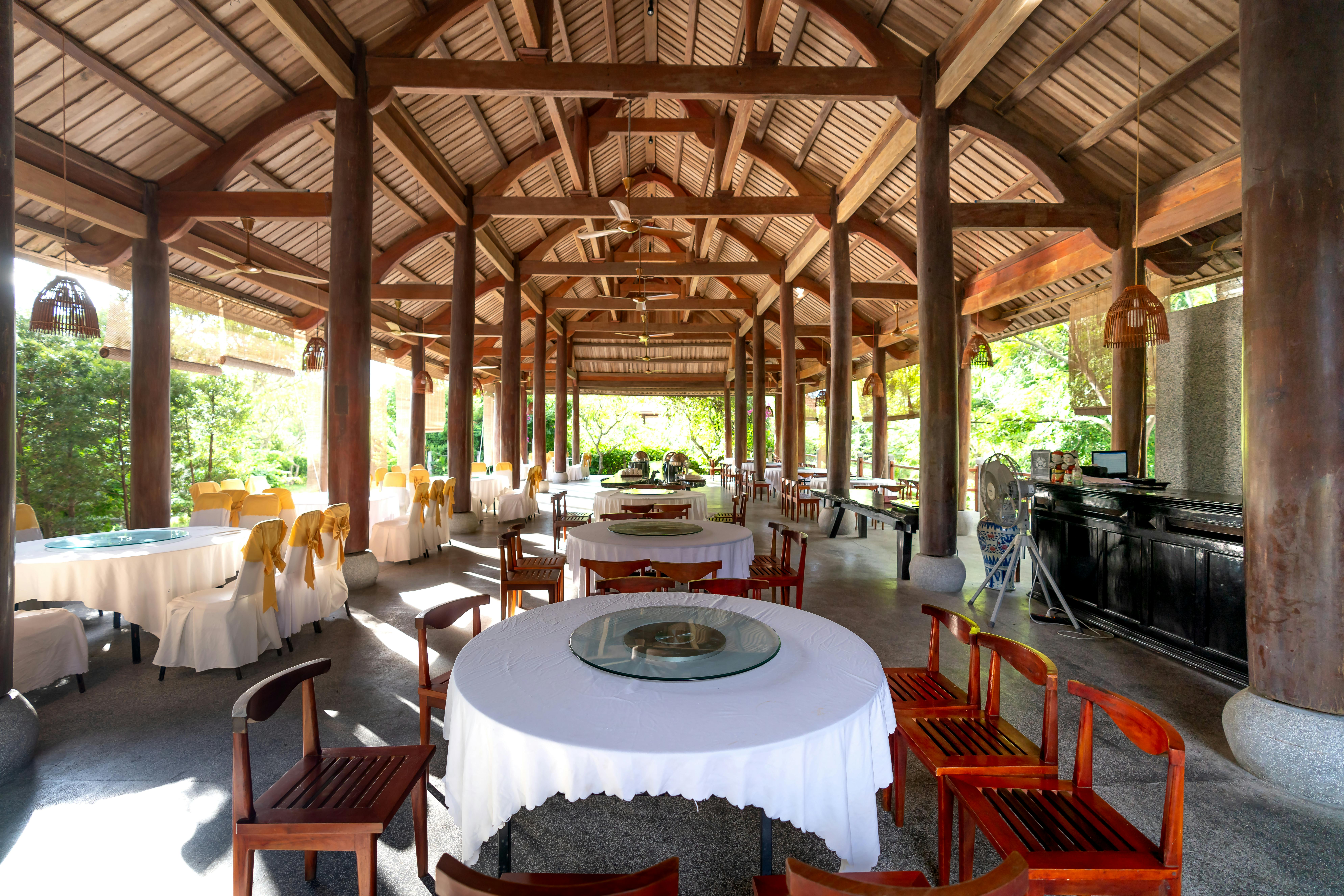 Covered dining pavilion with wooden beams and elegantly set tables in a tropical resort setting for the multigen family dining context