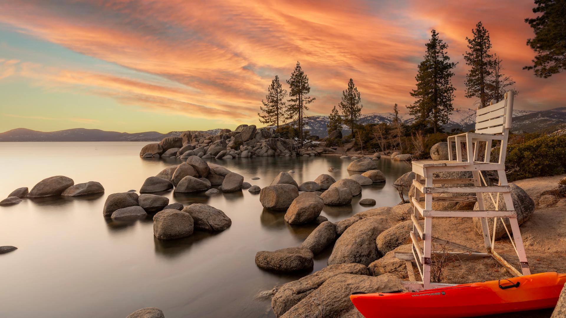 Lake Tahoe rocky shoreline with canoe and mountain backdrop