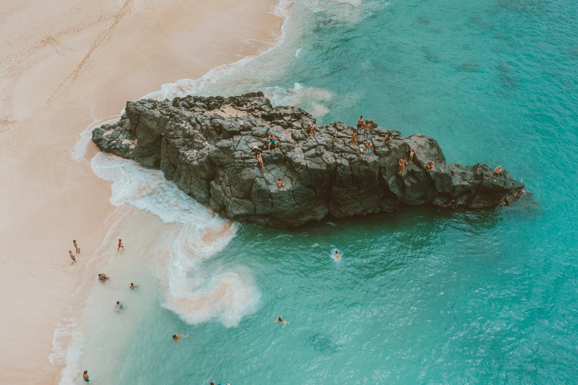 People enjoying turquoise ocean water at Waimea Bay Oahu with sandy beach
