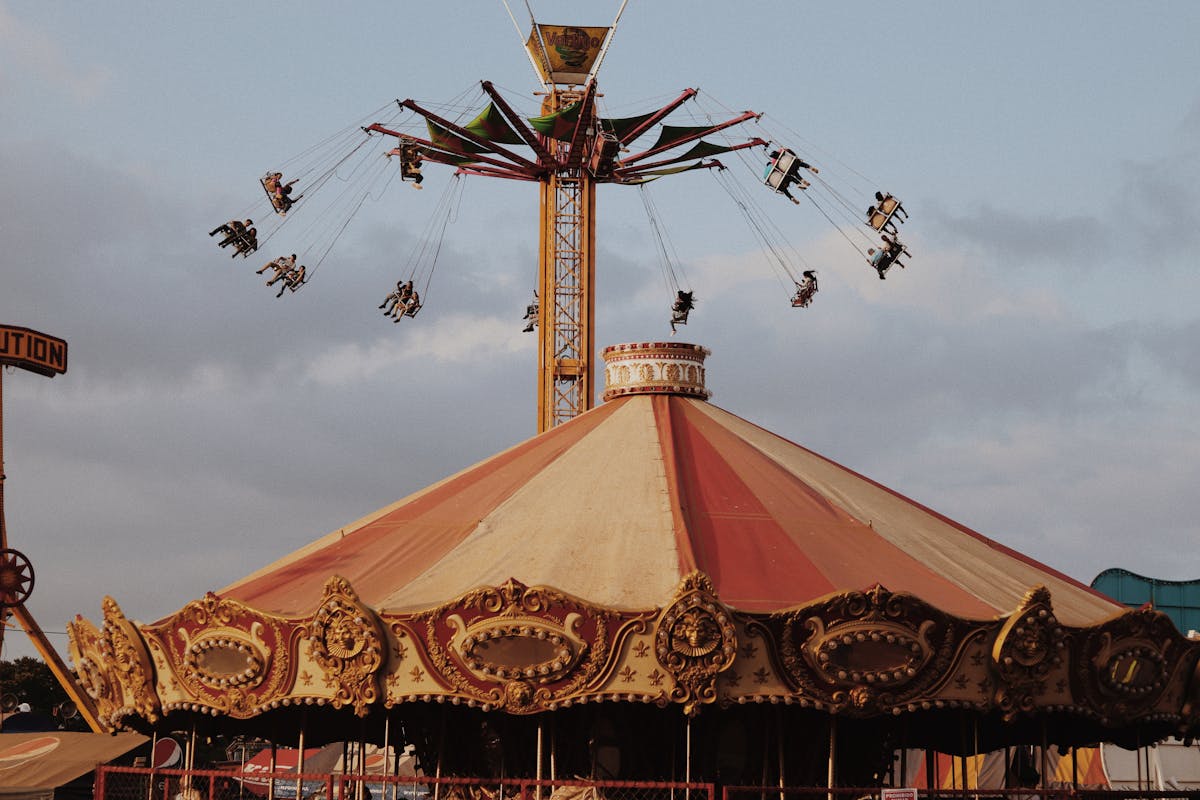 Carousel and swing rides at twilight with warm lights at amusement park