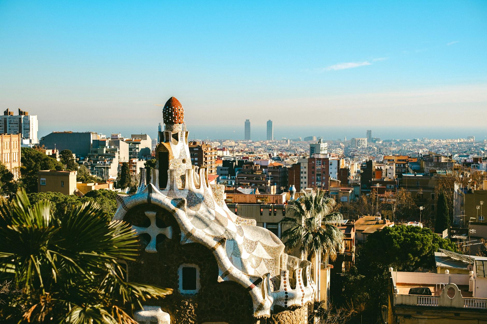 Aerial view of Park Guell's mosaic terrace and Gaudi architecture with Barcelona cityscape behind