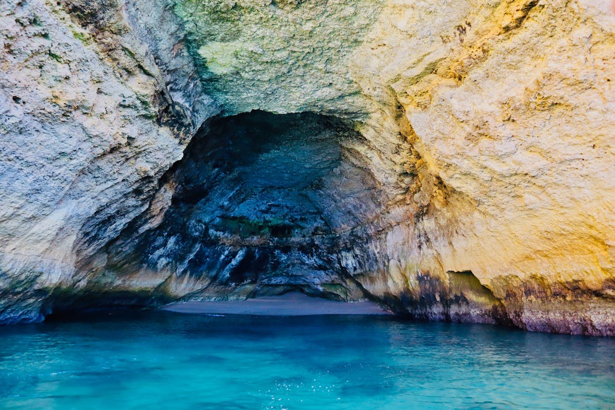 Turquoise sea cave along the Algarve coast in Portugal with golden rock walls