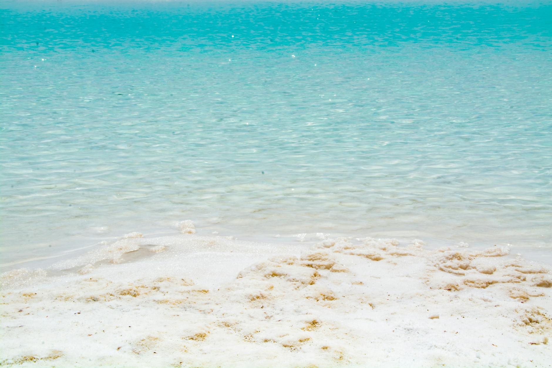 Shallow turquoise water and white sand at the shoreline &mdash; the lagoon-clear water effect that distinguishes Turks and Caicos beaches like Grace Bay