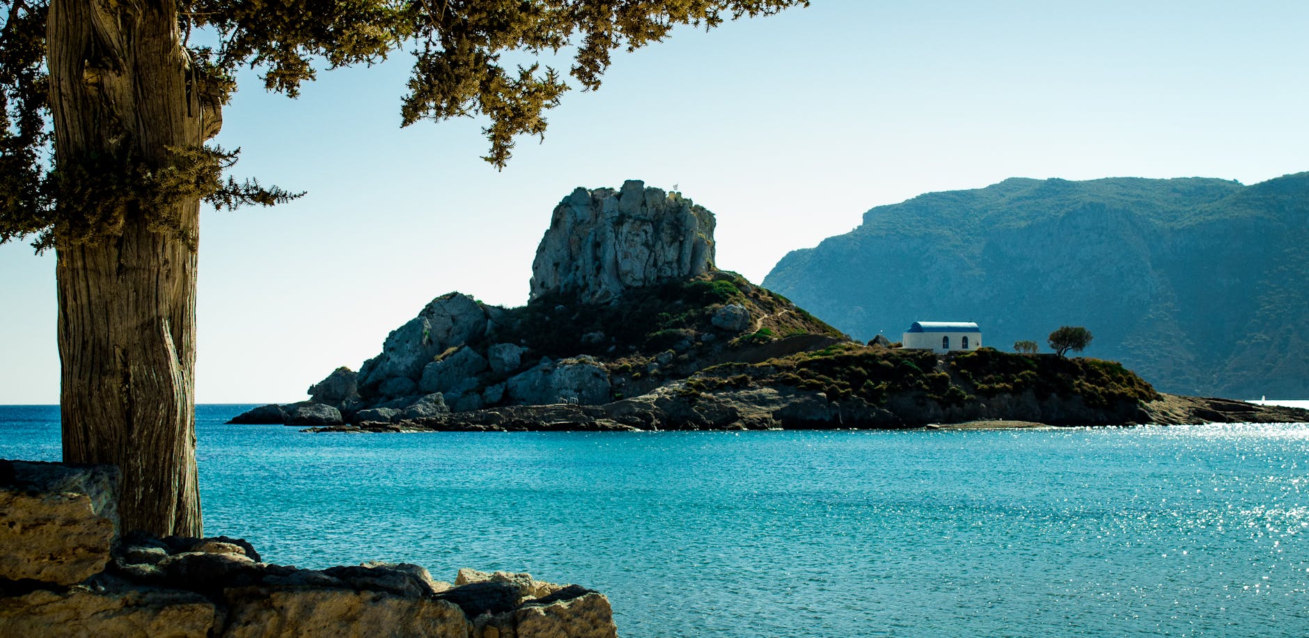 Rocky Kos island coastline with turquoise waters, a Rhodes vs Kos family holiday scene