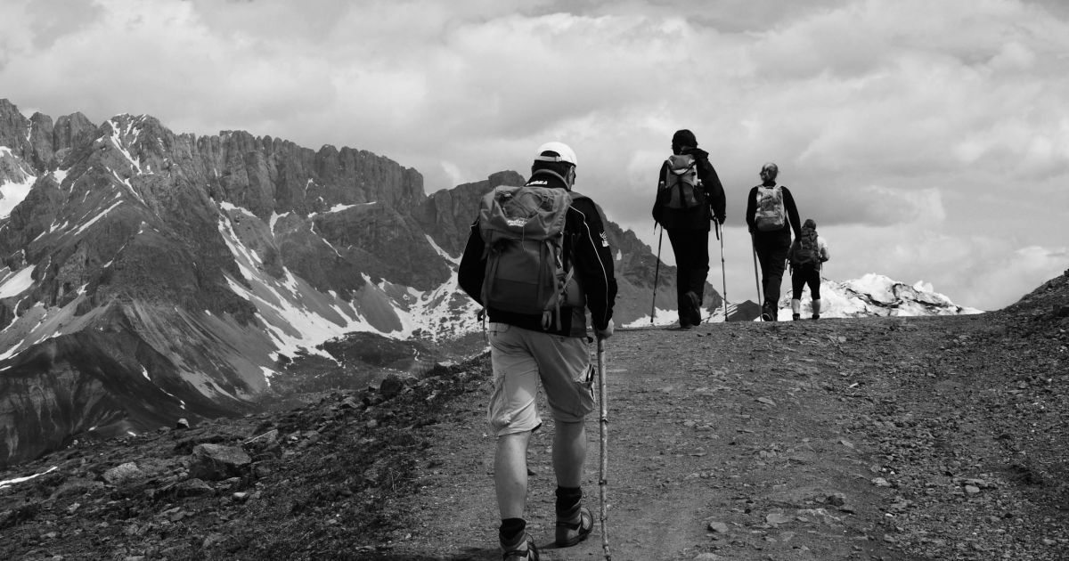 Father carrying child in hiking backpack on mountain trail
