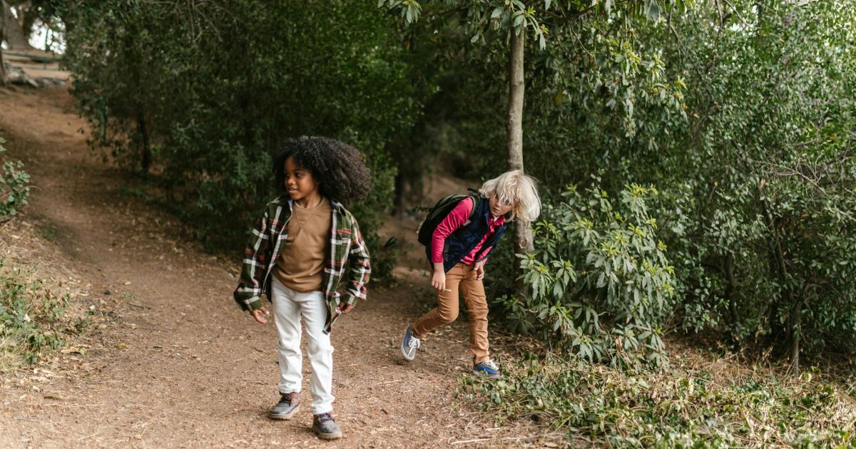 Father carrying child in hiking backpack on mountain trail