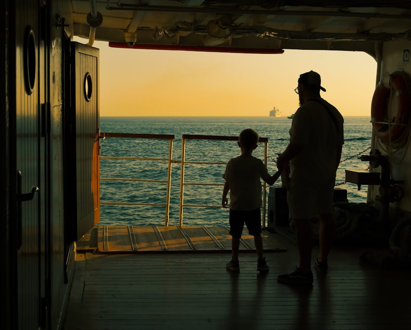 Father and son watching the ocean from a cruise ship deck at sunset