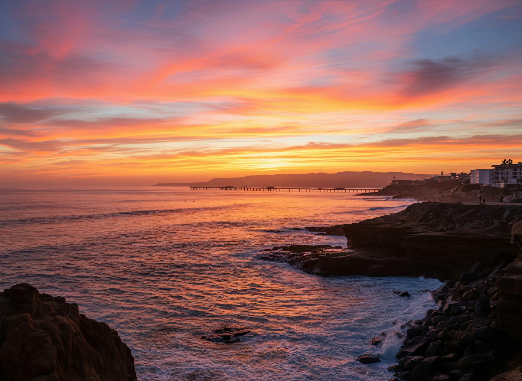 Dramatic sunset over San Diego coastline with ocean cliffs and pier