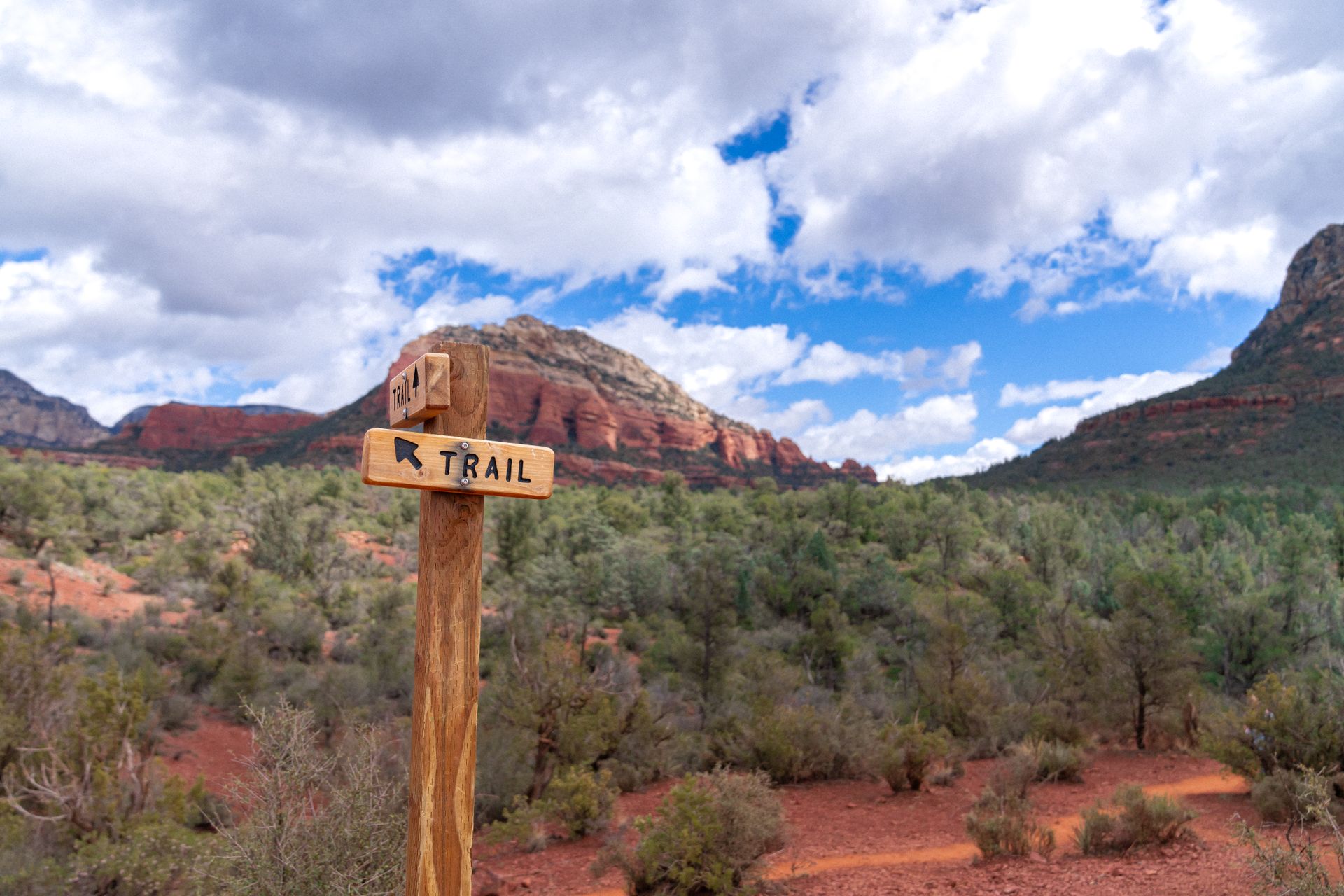 Wooden trail sign in Sedona's red rock landscape, under clear blue skies