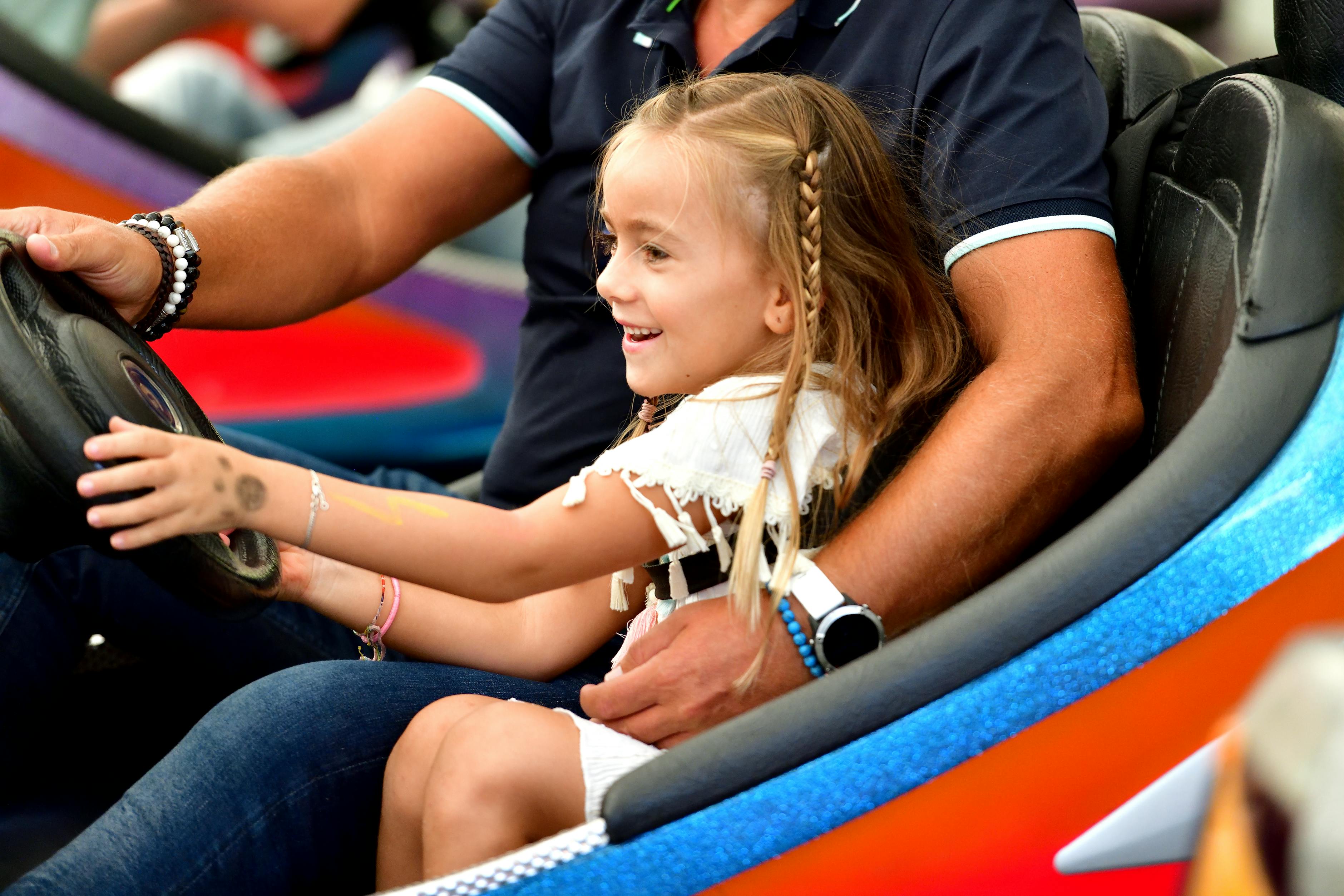 Father and daughter laughing together on a bumper car ride at a theme park &mdash; the family-joy moment that sensory-friendly accommodations preserve