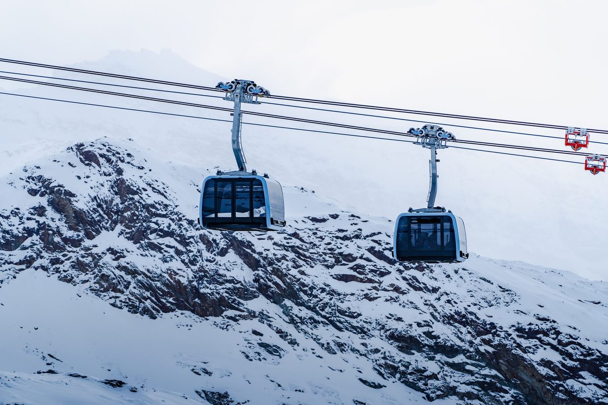 Two cable car cabins crossing snow-covered rock at Zermatt, the walk-on lift ride a non ski family pays for by the trip