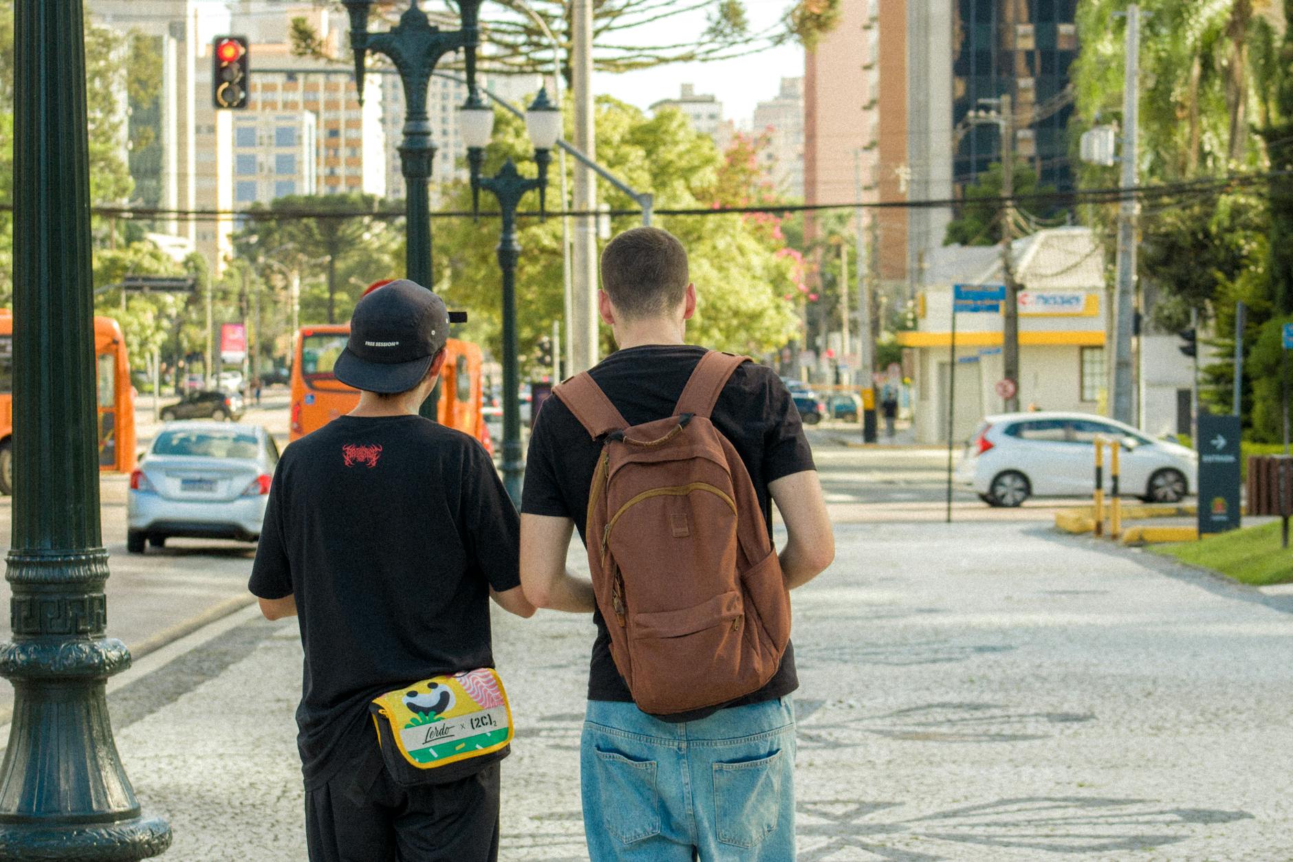 Two teenagers walking on a sunny urban street with backpacks exploring a city
