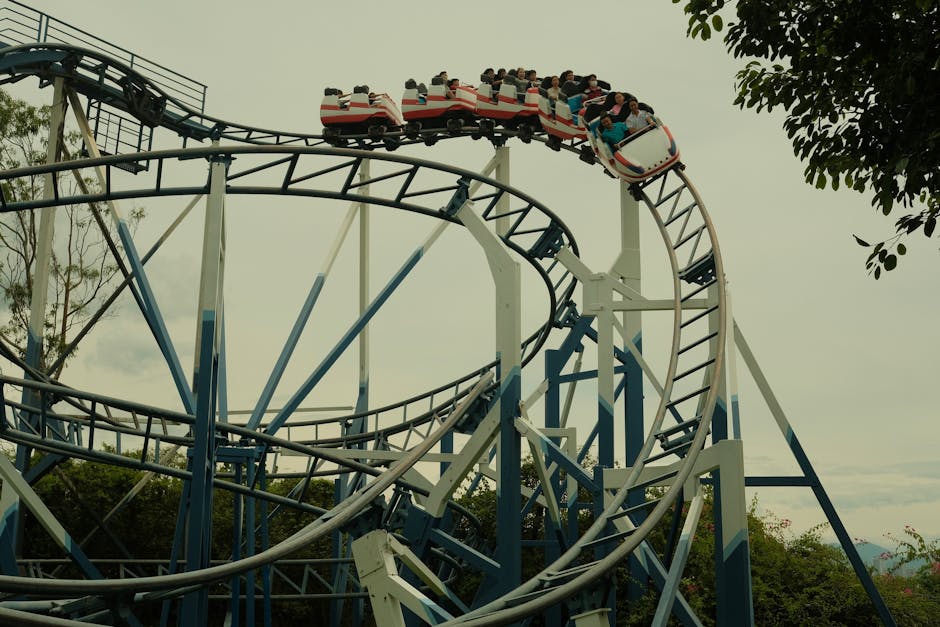 Roller coaster ride at a theme park during a sunny day with green trees