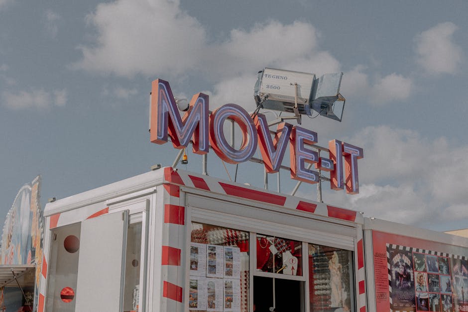 Ticket booth with neon signs at a sunny amusement park