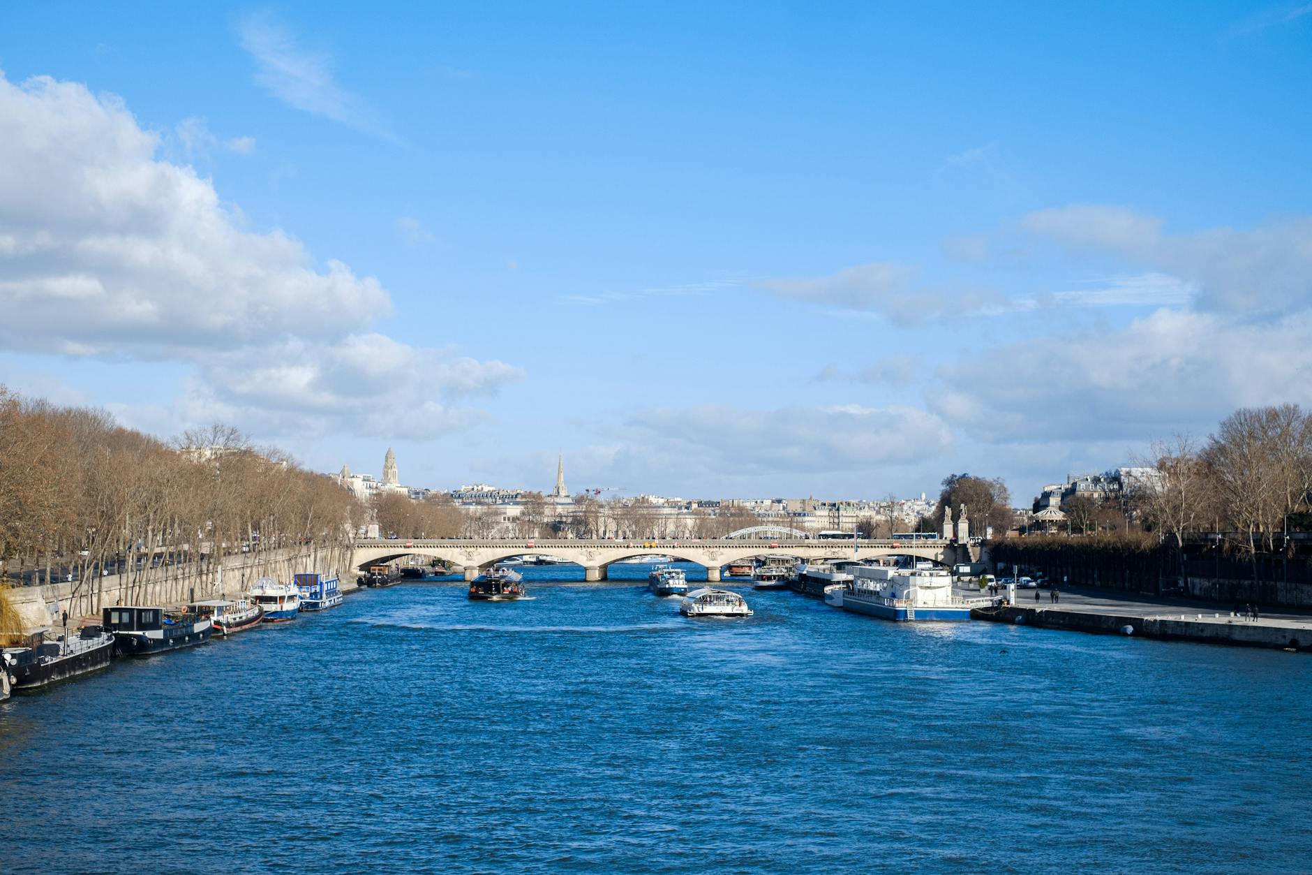 Seine River with tour boats and bridges under blue sky in Paris