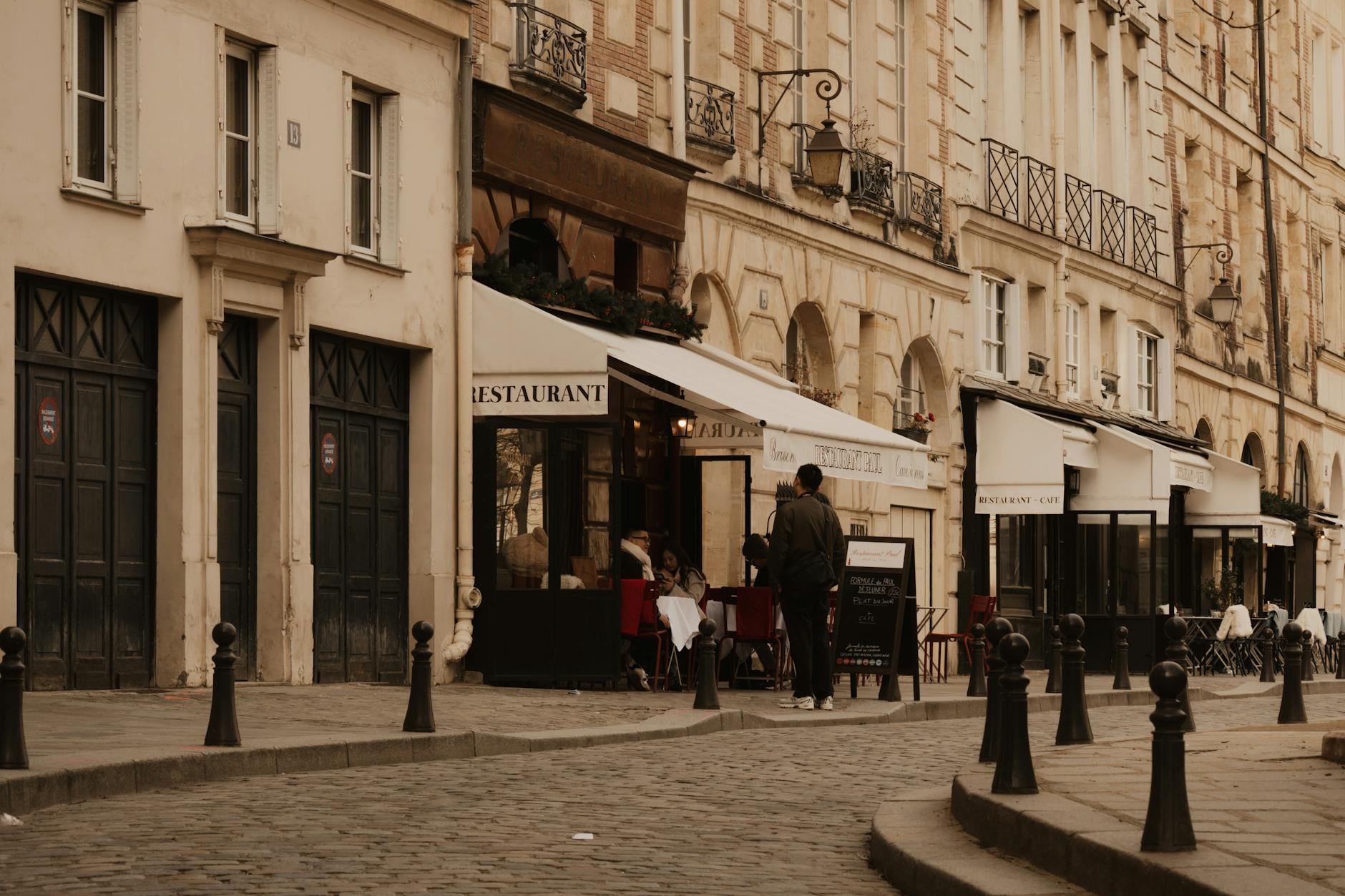 Cobblestone Parisian street lined with sidewalk cafes and classic architecture