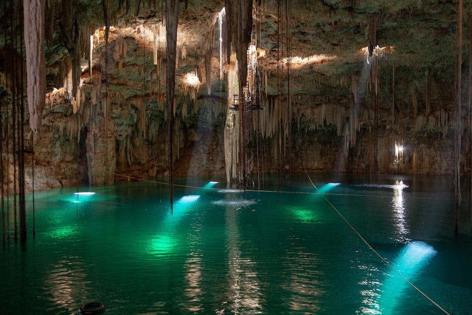Turquoise cenote pool inside limestone cave with stalactites in Yucatan Mexico