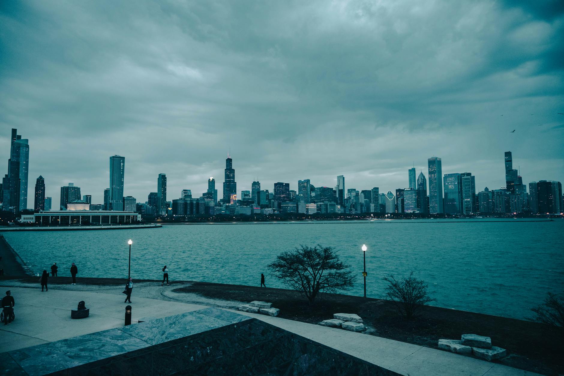Chicago skyline of tall skyscrapers reflected in Lake Michigan under a moody grey sky