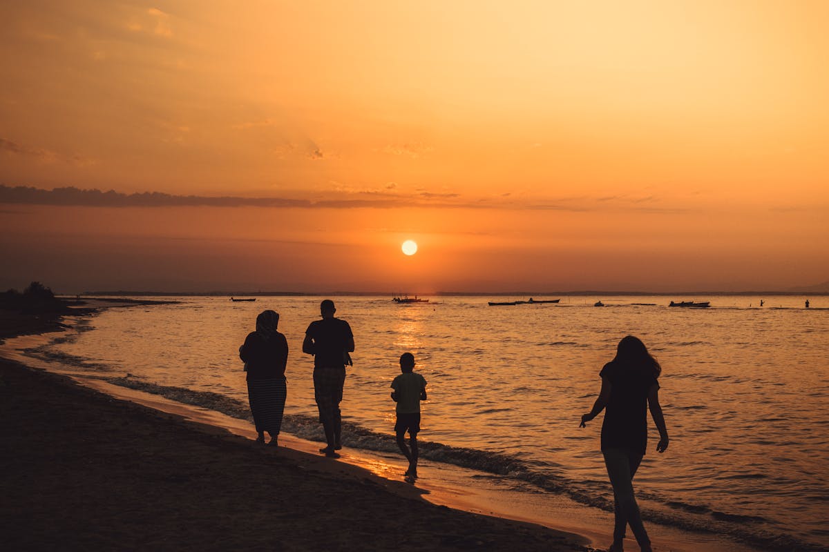 UK family walking along a Mediterranean beach at September sunset for a shoulder season holiday