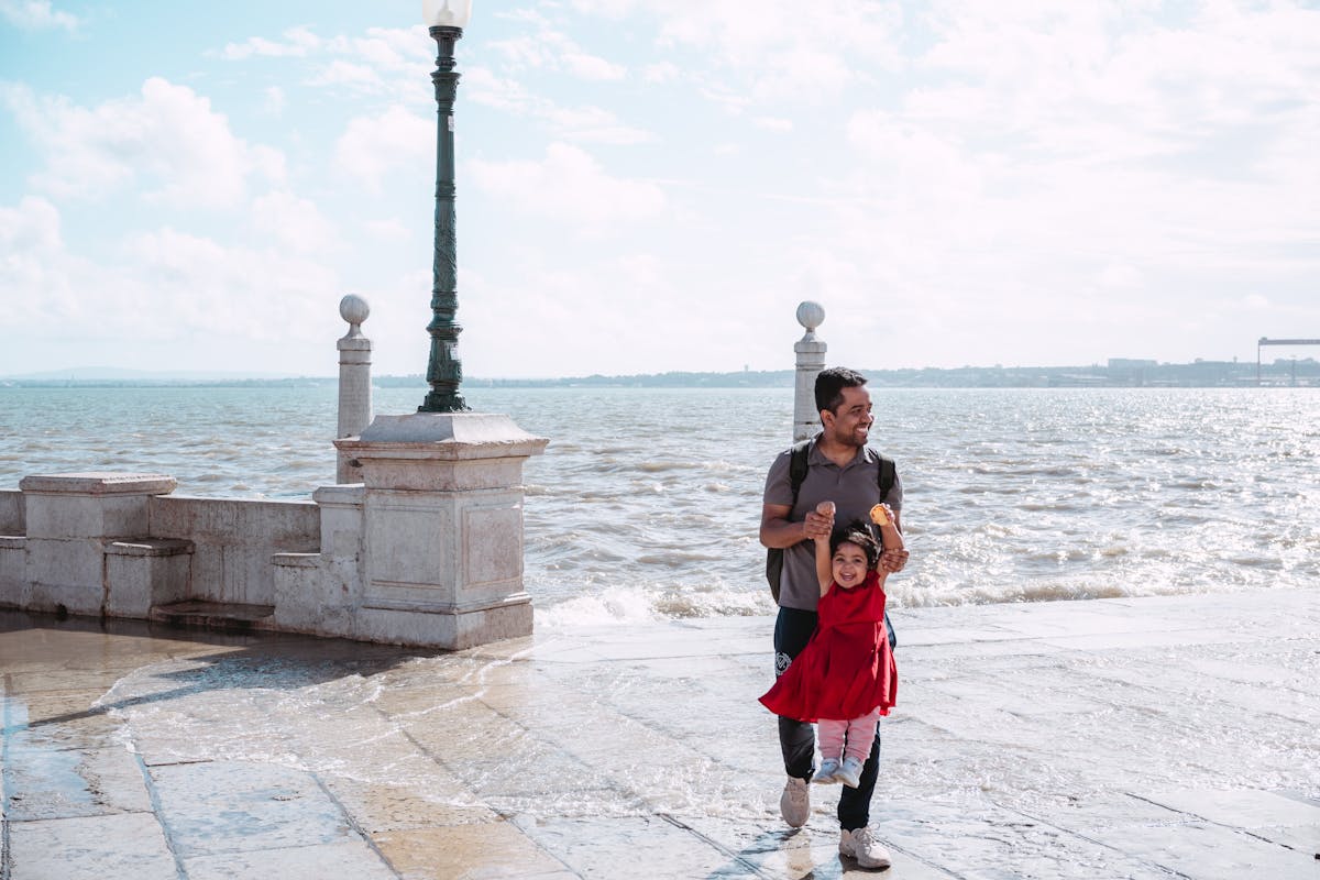 Father and daughter playing by the sea on a sunny family holiday day