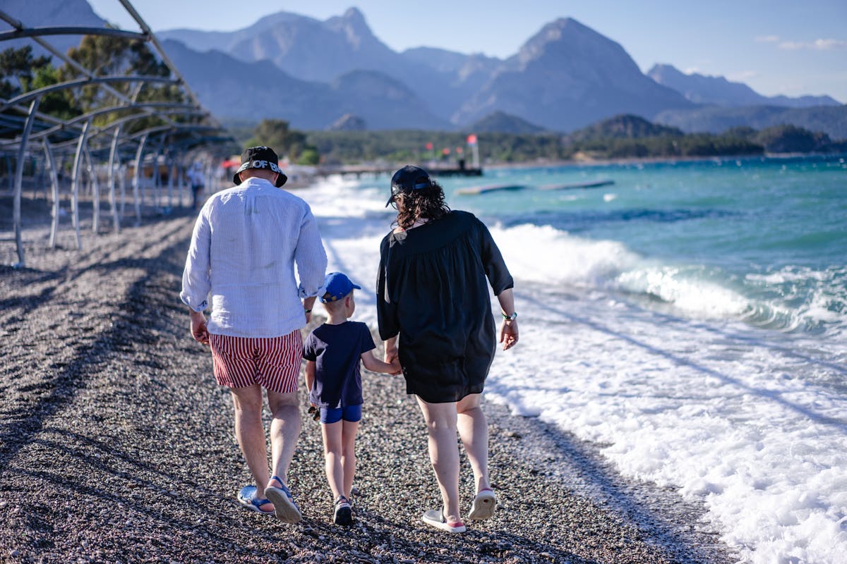 UK family walking along a Mediterranean beach during a half term holiday in sunny weather