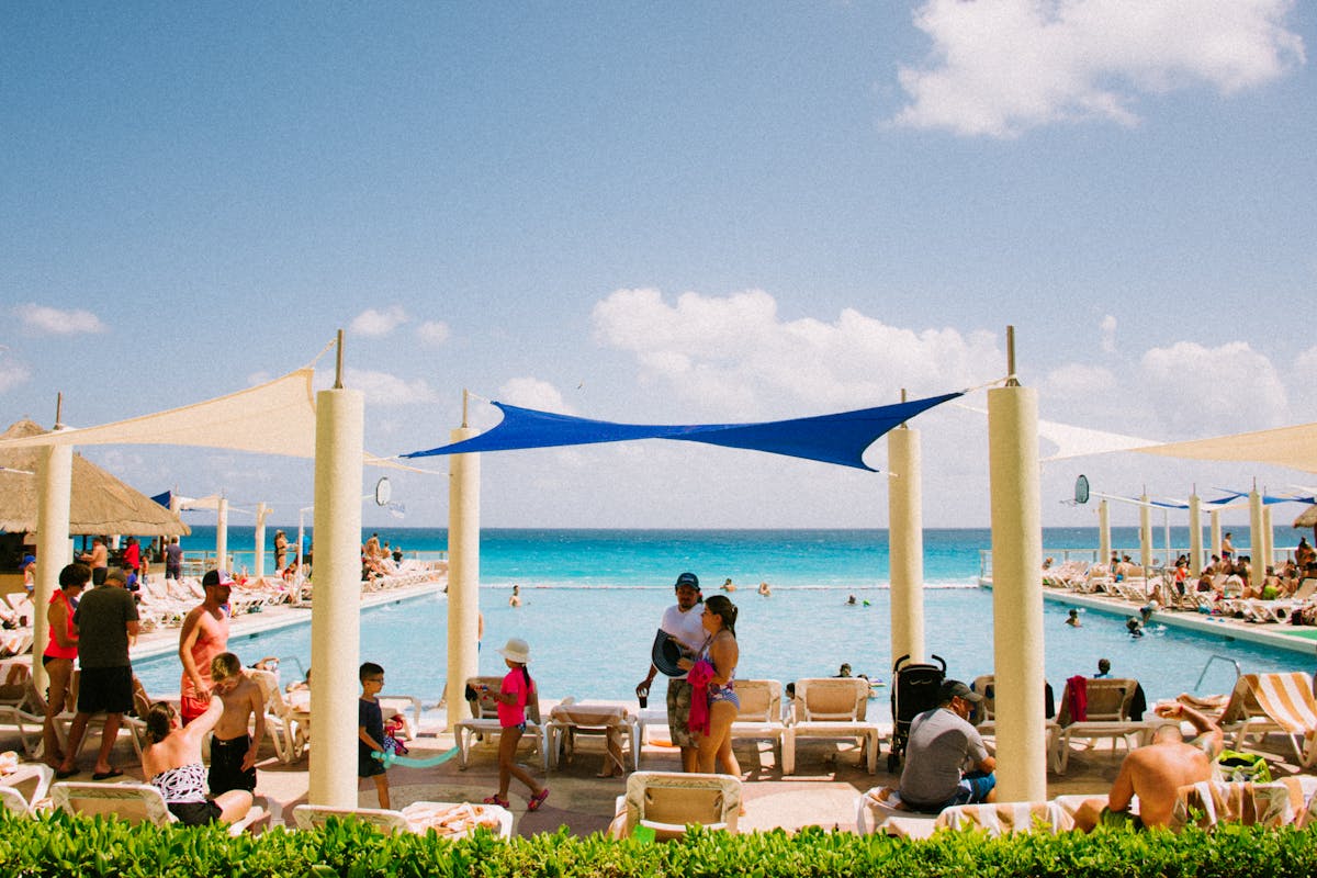 Families relaxing at a sunny resort pool overlooking the Mediterranean during UK school holidays