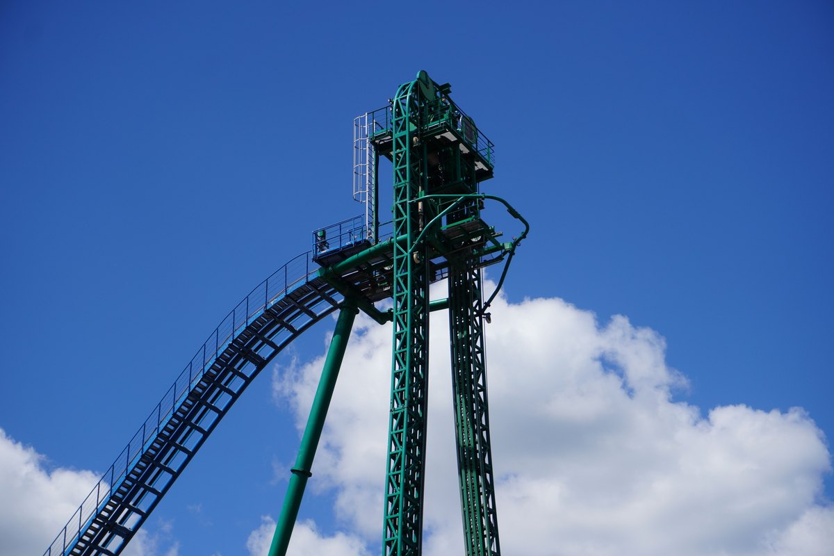 Green rollercoaster track climbing into a blue Florida sky, the coaster scale Epic Universe's headliners compete at