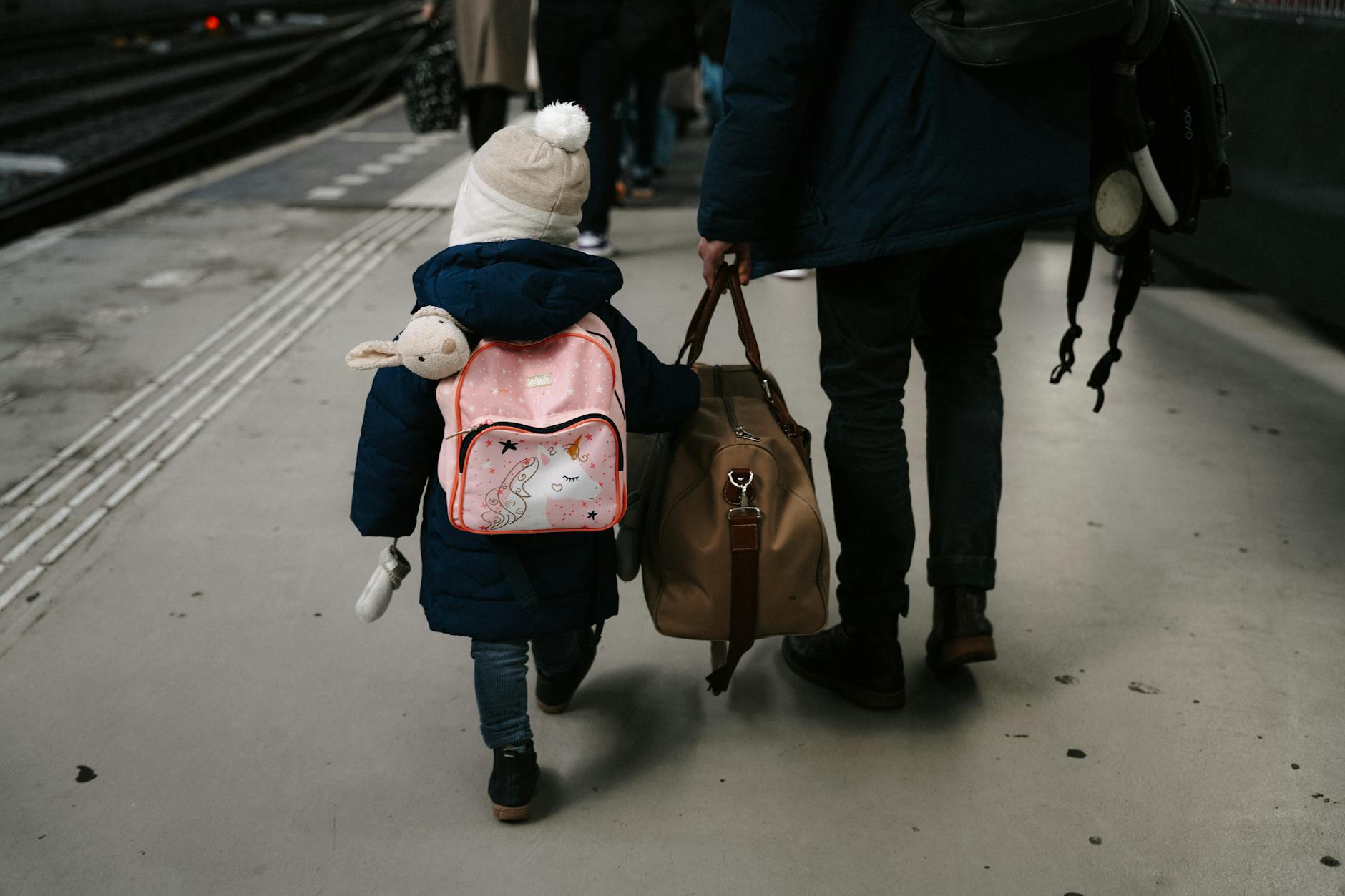 Child and adult boarding a train at a European station, a train hop on a US family Europe trip
