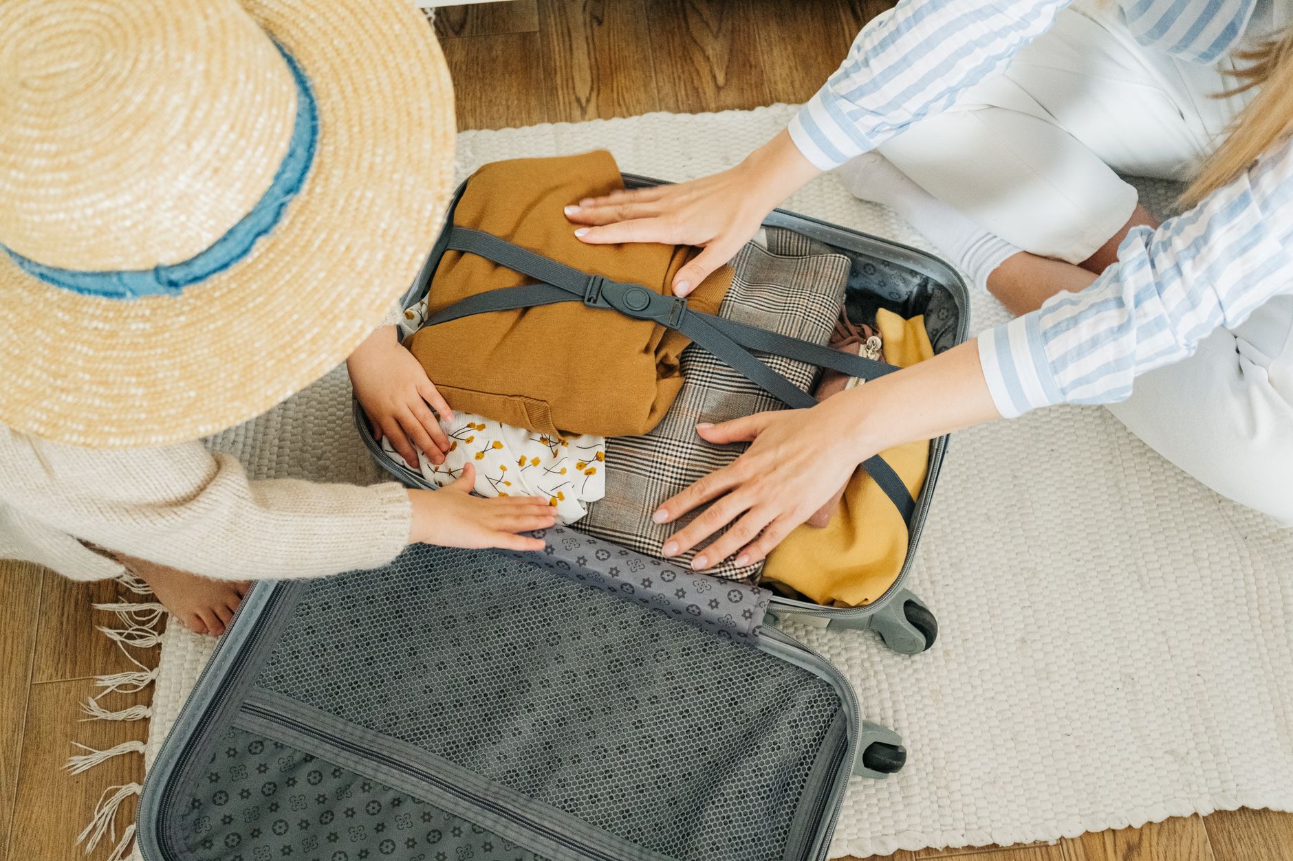 Family of four packing a suitcase before a vacation, planning around the hidden cost stack each vacation type carries