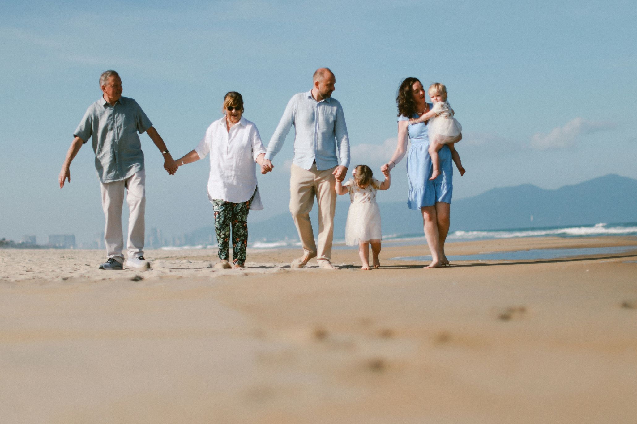 Three generations of a family walking a beach together on a trip organized with a shared itinerary