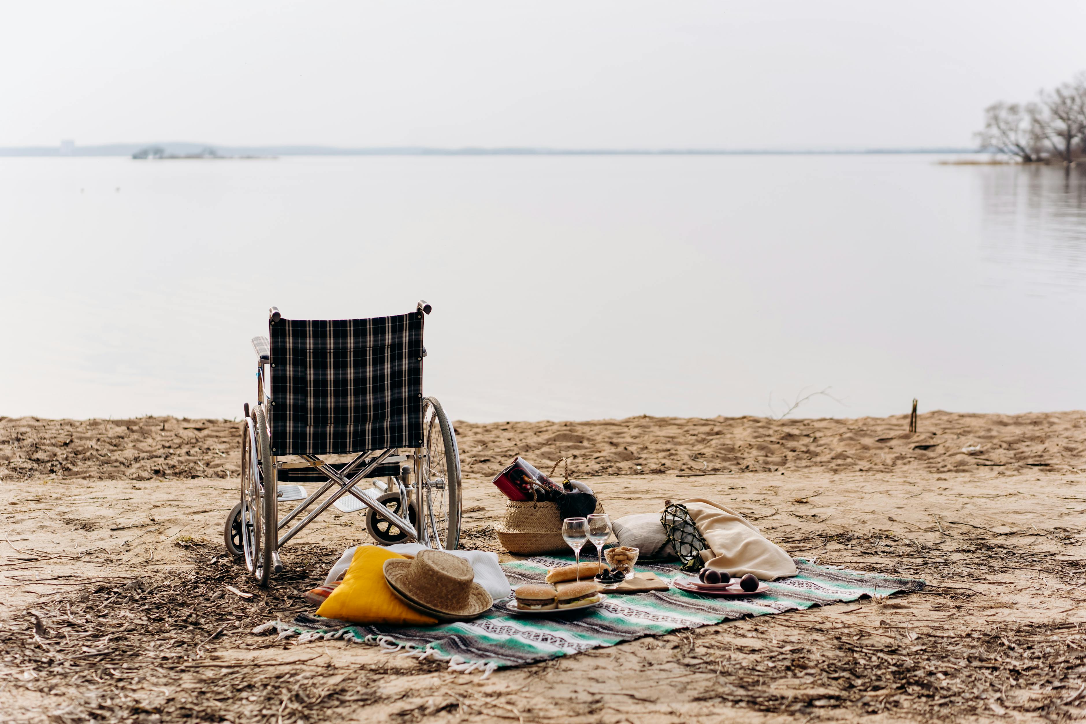 Wheelchair-accessible beach picnic with food and a blanket on the sand &mdash; the quiet, lived-in moment of an accessible vacation