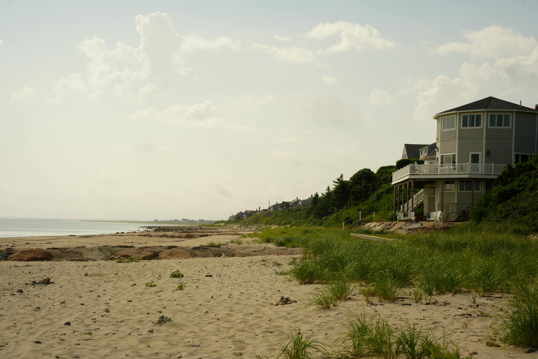Coastal beach house with sand dunes and grass near the ocean shoreline