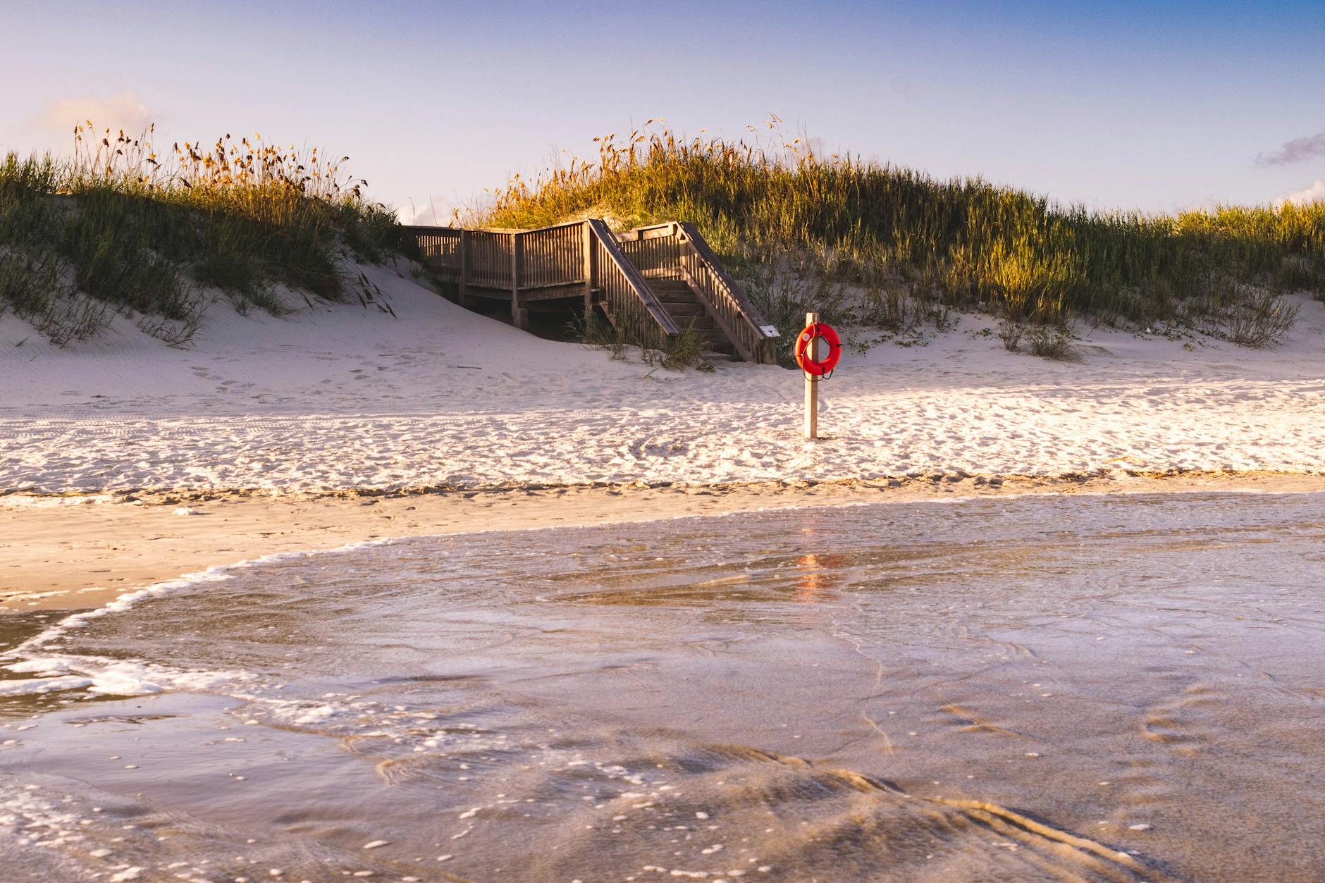 Peaceful beach scene with lifebuoy and wooden stairs leading to the sandy shore
