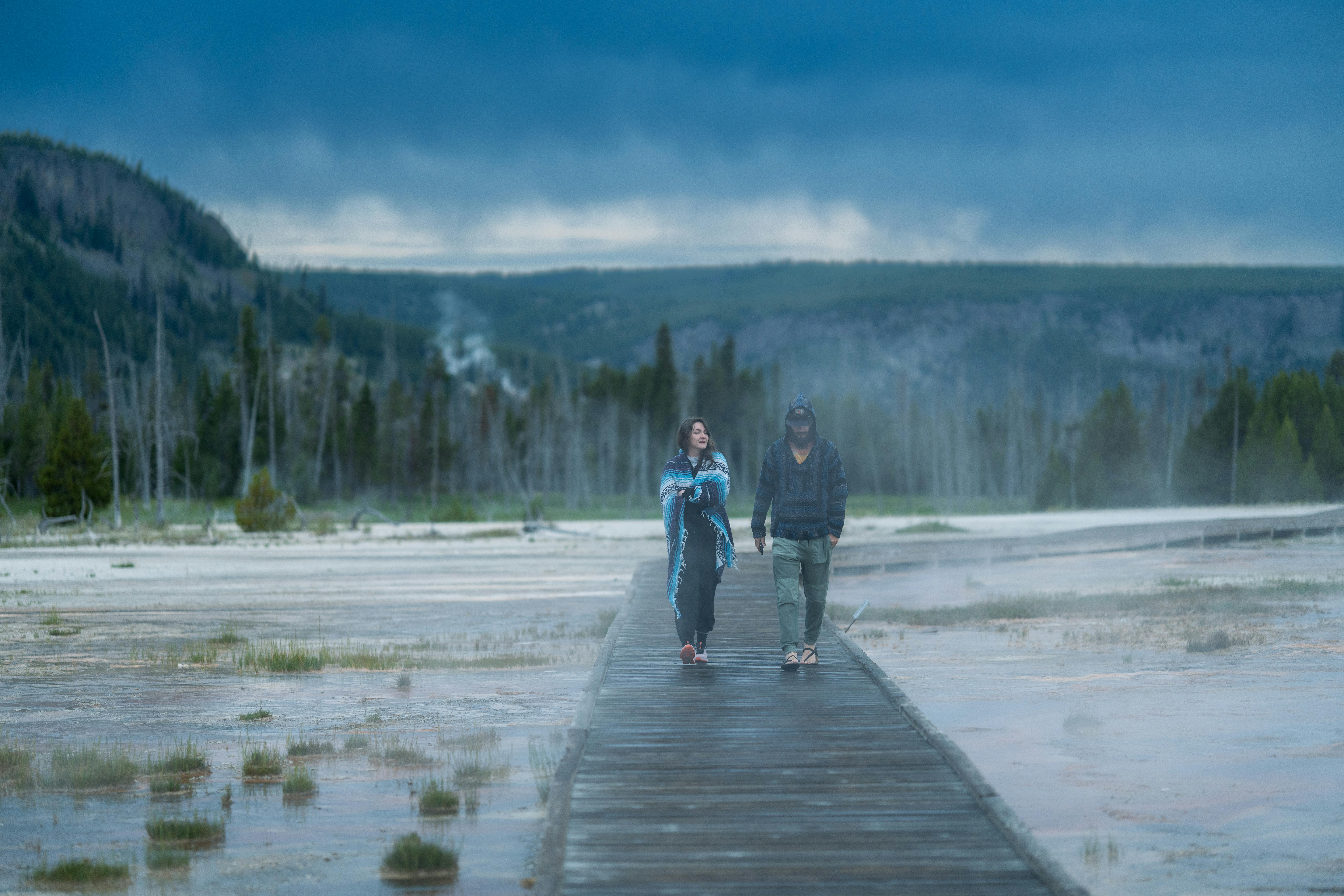Couple strolling on a boardwalk in misty Yellowstone National Park representing the stroller-accessible boardwalk-heavy toddler experience