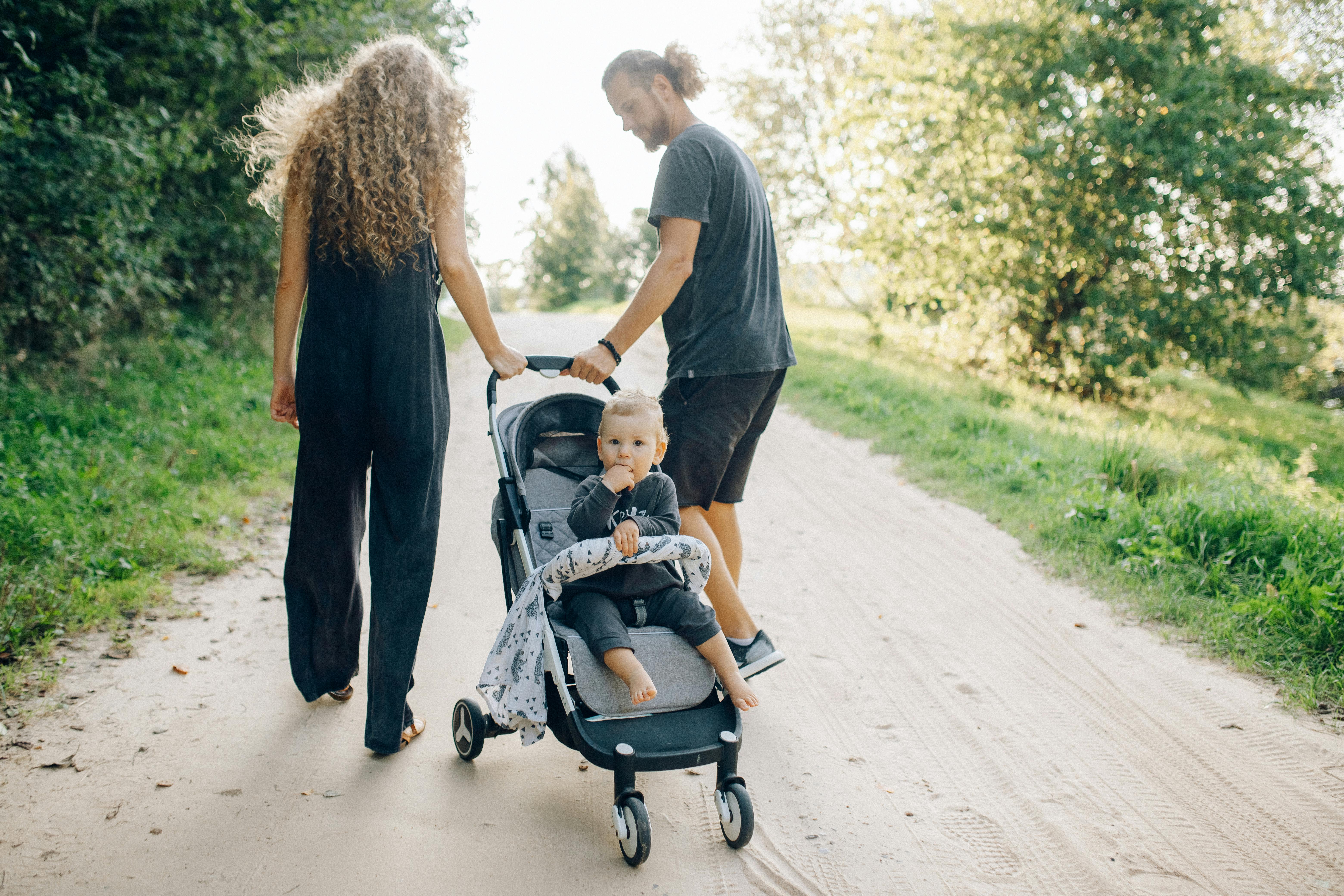 Happy family walking with a toddler in stroller on a sunny day representing the practical toddler-pace itinerary the article frames